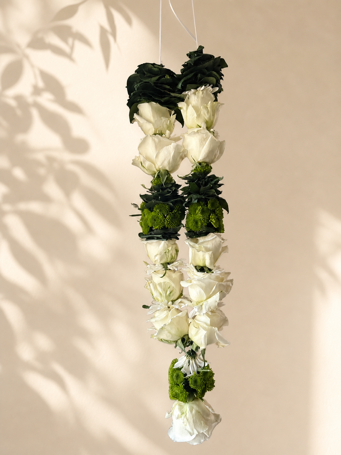 Ivory rose and green mum hanging garland on warm ivory leaf-shadow backdrop