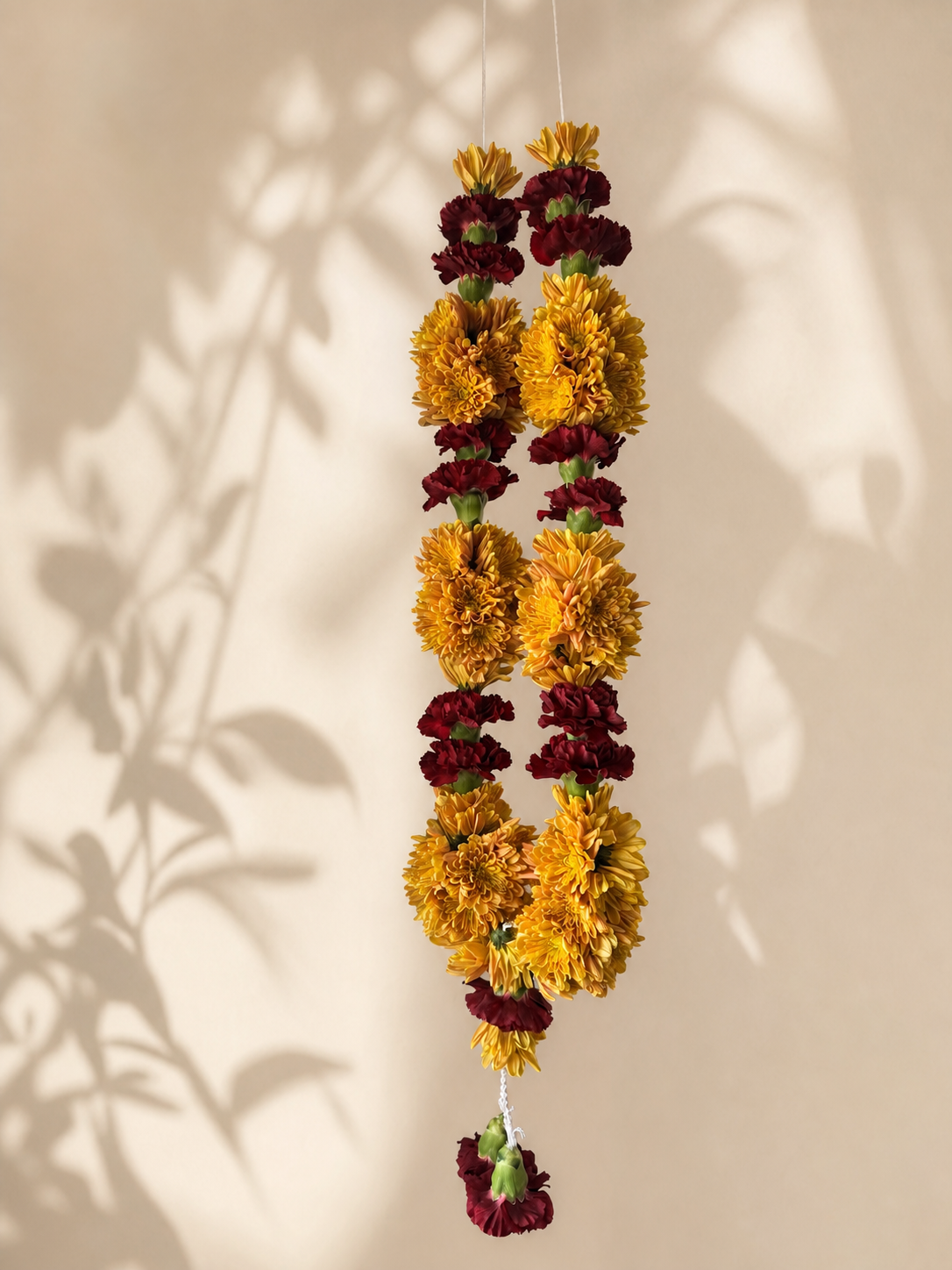 Marigold and burgundy garland alternate product view on ivory leaf-shadow backdrop