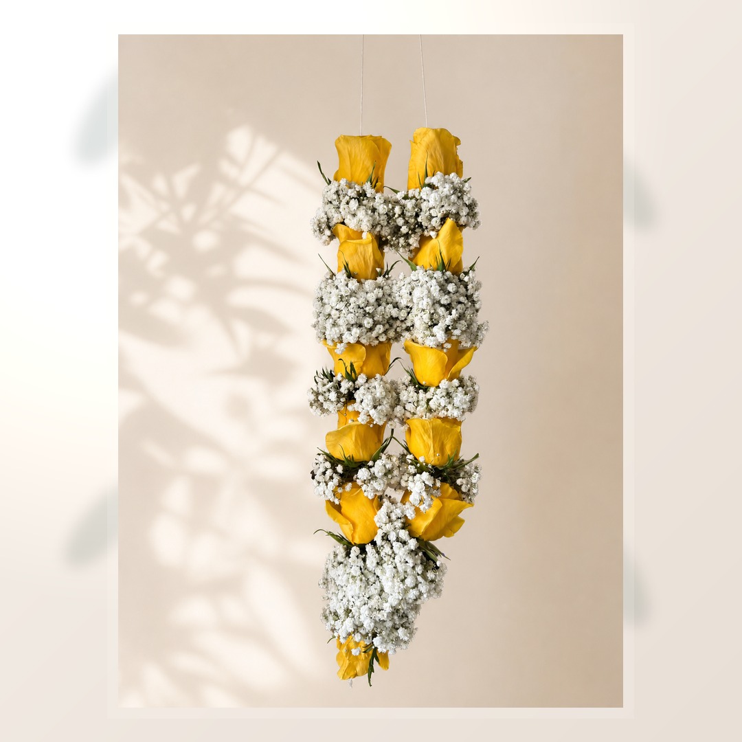 Golden yellow rose and white baby's breath hanging garland on ivory leaf-shadow backdrop
