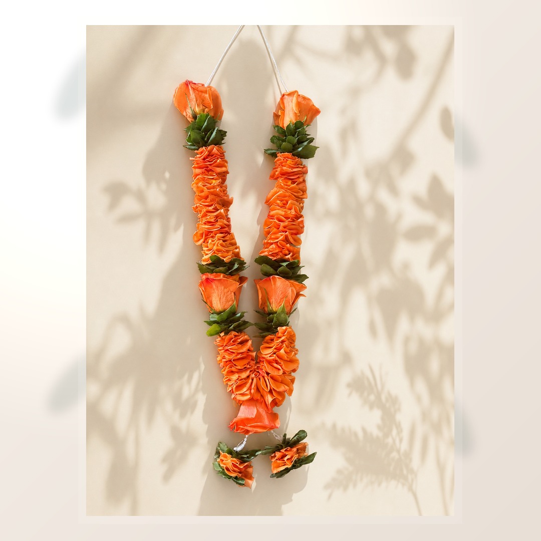 Orange rose and green foliage garland pair on clean ivory leaf-shadow backdrop