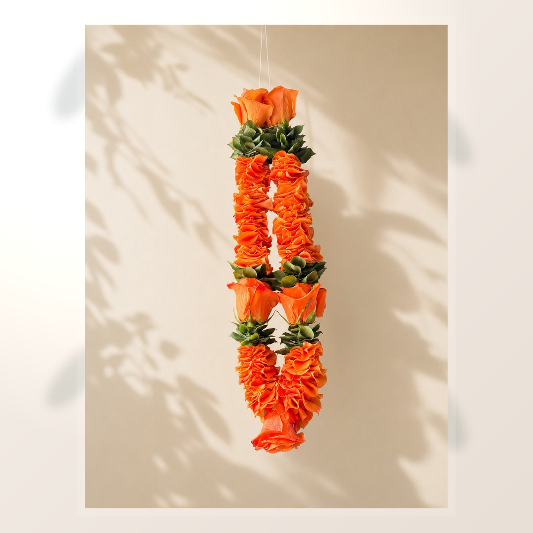 Orange rose and green foliage hanging garland on clean ivory leaf-shadow backdrop