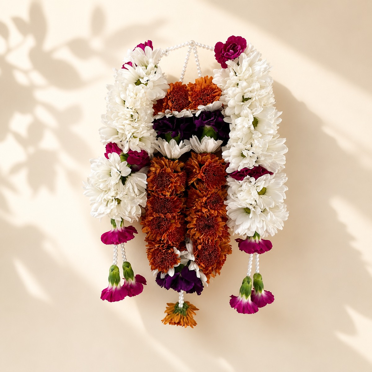 Autumn daisy orchid pearl mala with floral tassels on warm ivory leaf-shadow backdrop