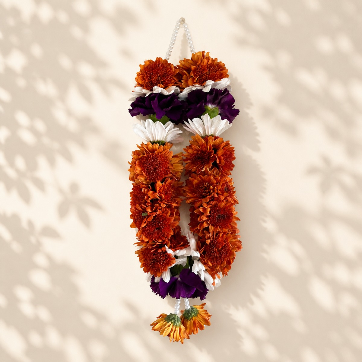 Copper daisy and purple hanging mala on warm ivory leaf-shadow backdrop